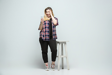 Image showing Young caucasian woman in casual wear on gray background. Bodypositive female character, plus size businesswoman