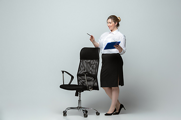 Image showing Young caucasian woman in office attire on gray background. Bodypositive female character. plus size businesswoman