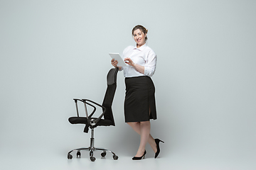 Image showing Young caucasian woman in office attire on gray background. Bodypositive female character. plus size businesswoman