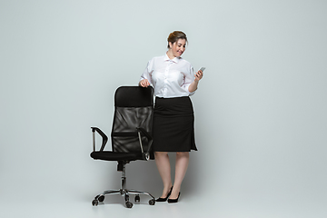 Image showing Young caucasian woman in office attire on gray background. Bodypositive female character. plus size businesswoman