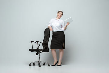 Image showing Young caucasian woman in office attire on gray background. Bodypositive female character. plus size businesswoman