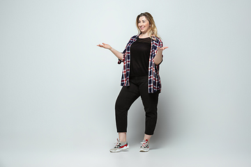 Image showing Young caucasian woman in casual wear on gray background. Bodypositive female character, plus size businesswoman