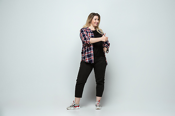 Image showing Young caucasian woman in casual wear on gray background. Bodypositive female character, plus size businesswoman