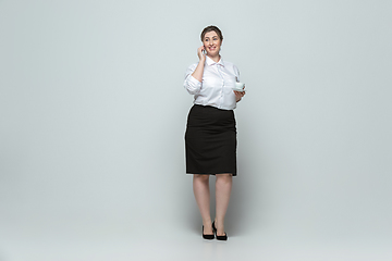 Image showing Young caucasian woman in office attire on gray background. Bodypositive female character. plus size businesswoman