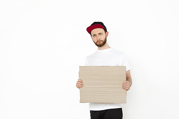 Image showing Young man protesting with blank board, sign isolated on white studio background