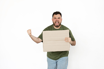 Image showing Young man protesting with blank board, sign isolated on white studio background