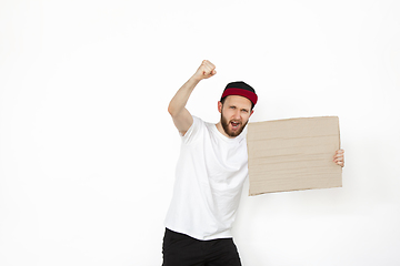 Image showing Young man protesting with blank board, sign isolated on white studio background