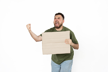 Image showing Young man protesting with blank board, sign isolated on white studio background