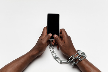 Image showing Close up of human hand using smartphone with blank black screen. Tied with chain, addiction