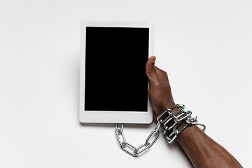 Image showing Close up of human hand using tablet with blank black screen. Tied with chain, addiction