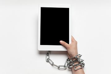 Image showing Close up of human hand using tablet with blank black screen. Tied with chain, addiction