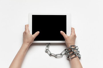 Image showing Close up of human hand using tablet with blank black screen. Tied with chain, addiction