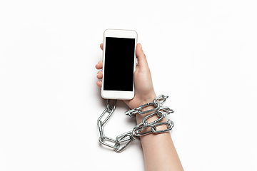 Image showing Close up of human hand using smartphone with blank black screen. Tied with chain, addiction