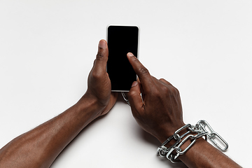 Image showing Close up of human hand using smartphone with blank black screen. Tied with chain, addiction