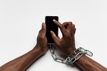 Image showing Close up of human hand using smartphone with blank black screen. Tied with chain, addiction