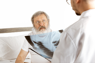 Image showing Elderly old man recovering in a hospital bed isolated on white