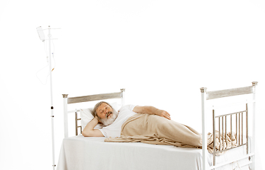 Image showing Elderly old man recovering in a hospital bed isolated on white