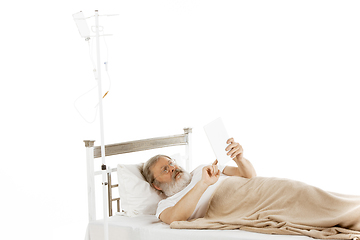 Image showing Elderly old man recovering in a hospital bed isolated on white