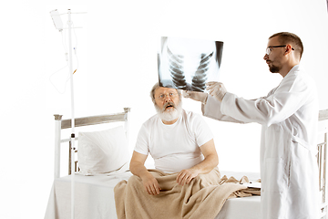 Image showing Elderly old man recovering in a hospital bed isolated on white