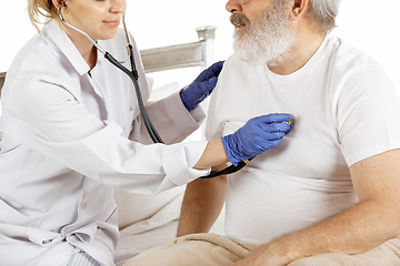 Image showing Elderly old man recovering in a hospital bed isolated on white