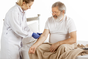 Image showing Elderly old man recovering in a hospital bed isolated on white