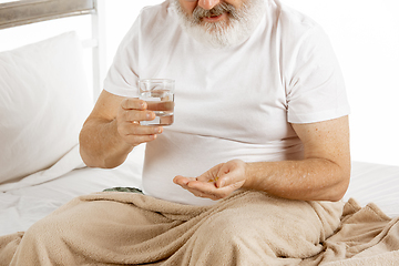 Image showing Elderly old man recovering in a hospital bed isolated on white