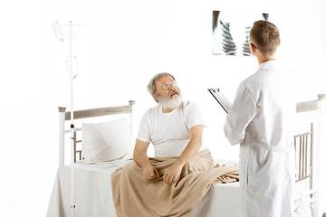 Image showing Elderly old man recovering in a hospital bed isolated on white