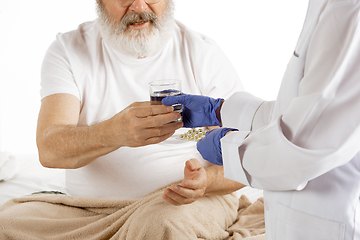 Image showing Elderly old man recovering in a hospital bed isolated on white