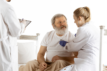 Image showing Elderly old man recovering in a hospital bed isolated on white