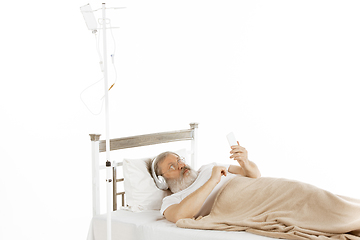 Image showing Elderly old man recovering in a hospital bed isolated on white