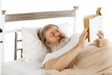 Image showing Elderly old man recovering in a hospital bed isolated on white