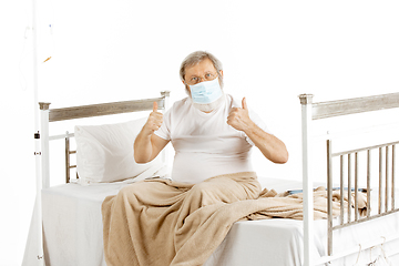 Image showing Elderly old man recovering in a hospital bed isolated on white