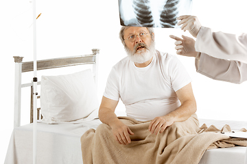 Image showing Elderly old man recovering in a hospital bed isolated on white