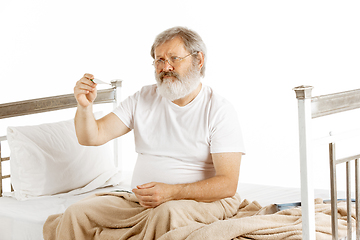 Image showing Elderly old man recovering in a hospital bed isolated on white