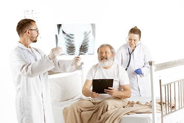 Image showing Elderly old man recovering in a hospital bed isolated on white