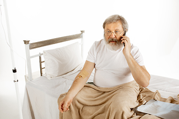 Image showing Elderly old man recovering in a hospital bed isolated on white