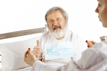 Image showing Elderly old man recovering in a hospital bed isolated on white