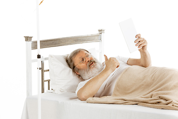 Image showing Elderly old man recovering in a hospital bed isolated on white