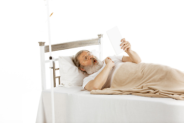 Image showing Elderly old man recovering in a hospital bed isolated on white