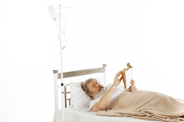 Image showing Elderly old man recovering in a hospital bed isolated on white