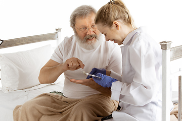 Image showing Elderly old man recovering in a hospital bed isolated on white