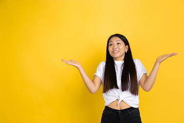 Image showing Portrait of young asian woman isolated on yellow studio background