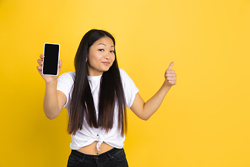 Image showing Portrait of young asian woman isolated on yellow studio background