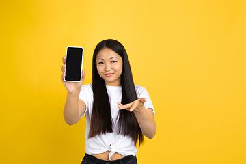 Image showing Portrait of young asian woman isolated on yellow studio background