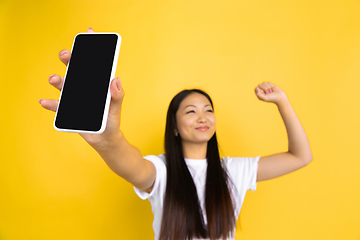 Image showing Portrait of young asian woman isolated on yellow studio background