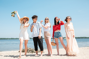 Image showing Seasonal feast at beach resort. Group of friends celebrating, resting, having fun on the beach in sunny summer day