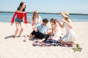 Image showing Seasonal feast at beach resort. Group of friends celebrating, resting, having fun on the beach in sunny summer day