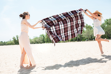 Image showing Seasonal feast at beach resort. Happy girls, friends celebrating, resting, having fun on the beach in sunny summer day