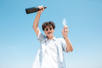 Image showing Seasonal feast at beach resort. Happy stylish boy celebrating, resting, having fun on the beach in sunny summer day