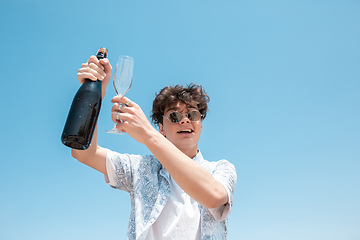 Image showing Seasonal feast at beach resort. Happy stylish boy celebrating, resting, having fun on the beach in sunny summer day